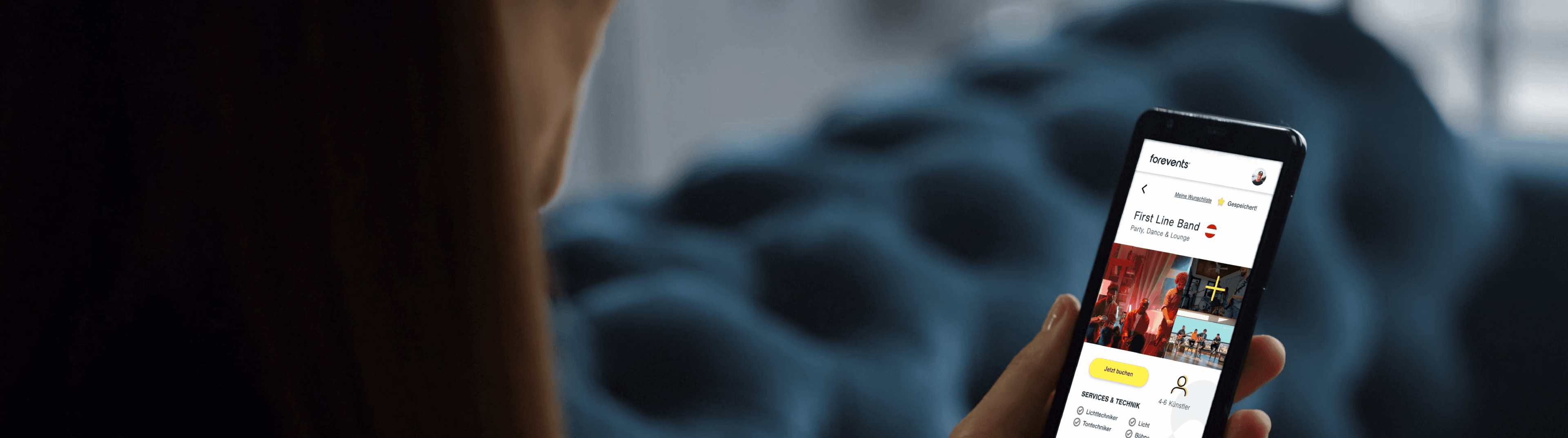 Person holding a smartphone displaying a music streaming app interface, with playlists and a search bar visible.